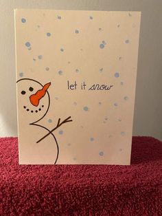 a card with a snowman on it that says let it snow and has an orange nose