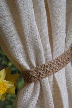 a close up of a curtain with some flowers in the foreground and one yellow flower on the other side