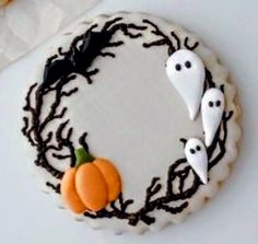 a decorated cake with white frosting and black icing on it, surrounded by halloween decorations