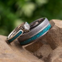 two wedding rings sitting on top of a rock next to each other with a diamond in the center