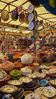 many plates and bowls are on display in a market