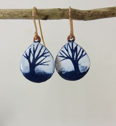 20mm long by 18mm wide teardrop dangle earrings in copper. Blue and white enamel has been added and fired in a kiln at 830 degrees. A tree design has been drawn through the white enamel revealing the blue beneath. They hang on rose gold plated earring wires. The backs have been textured with a tree stamp and polished to show the details. Posted out to you in an 830 degrees gift box with information about the enamelling process included. Each earring is different as they are all drawn by hand so Artistic Teardrop Enamel Jewelry, Hand Painted Blue Teardrop Jewelry, Degree Gift, Teardrop Dangle Earrings, Tree Stamp, Enamel Earrings, Gold Plated Earrings, Tree Designs, Enamel Jewelry