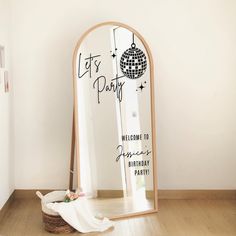 a mirror sitting on top of a hard wood floor next to a white wall with a disco ball