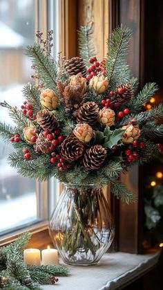 a vase filled with pine cones, berries and evergreens sitting on a window sill