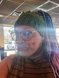 a woman wearing glasses and a knitted hat with dreadlocks on her head