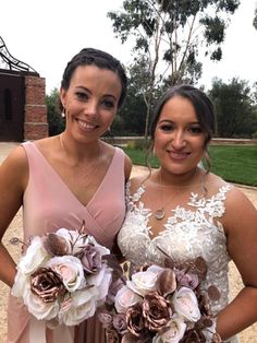 two women standing next to each other wearing dresses and holding bouquets in their hands