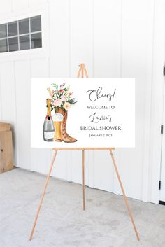 a welcome sign for a bridal shower with boots, flowers and champagne bottles on it