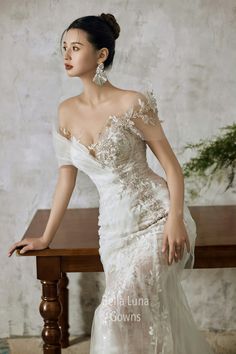 a woman in a white dress sitting on a wooden table