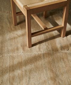 a wooden bench sitting on top of a carpeted floor next to a chair and table