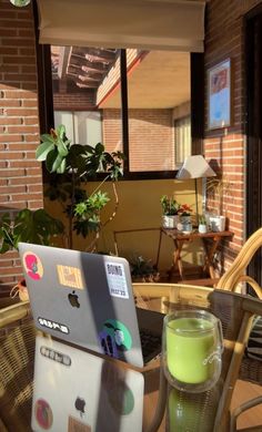 an open laptop computer sitting on top of a wooden table next to a green drink