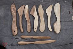 wooden spoons and knives are laid out on a piece of wood