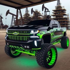 a black truck with neon green wheels parked in front of oil pumps