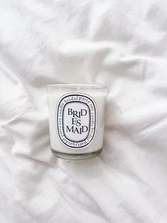 a white candle sitting on top of a bed next to a white comforter with the words brid as mad printed on it