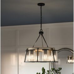 a chandelier hanging over a dining room table with potted plants on it