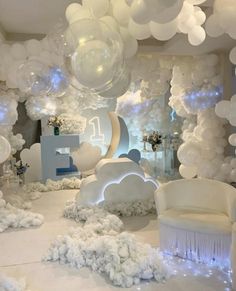 a room filled with balloons and white furniture next to a wall covered in snowflakes