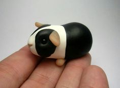 a small black and white cow sitting on top of someone's hand with it's eyes closed