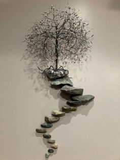 a tree that is growing out of some rocks on the wall next to a clock