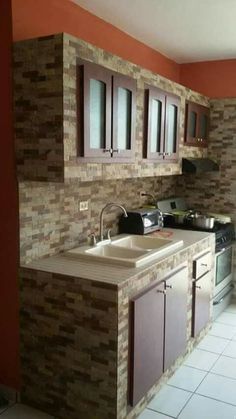 a kitchen that has a sink and some cupboards on the side of it in an orange walled room