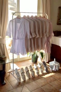 several pairs of shoes are sitting on the floor in front of a rack with clothes