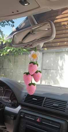 two strawberries hanging from the dash board of a car with flowers on each one