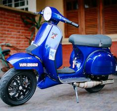 a blue scooter parked in front of a brick building