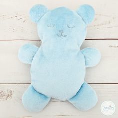 a blue teddy bear laying on top of a white wooden floor with its eyes closed