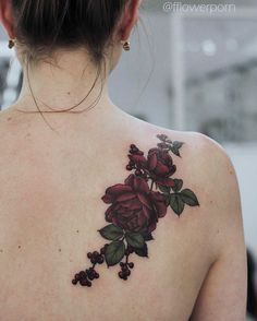 the back of a woman's shoulder with flowers and leaves tattooed on her chest