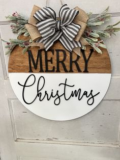 a merry christmas sign hanging on the side of a door with a bow and ribbon