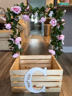 a wooden crate with pink flowers and a letter c on the front, sitting on a wood floor