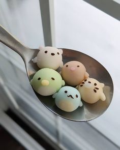 a spoon filled with small toy bears on top of a window sill