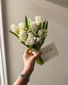 a person holding a bouquet of white flowers with a card in front of them that reads, thank you