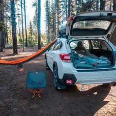 the back end of a white car with an open trunk and sleeping bag in it