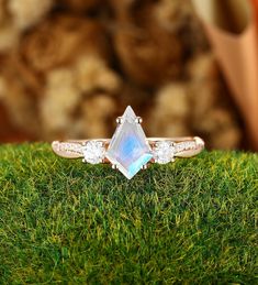 a ring with an iridescent stone in the center on top of some green grass