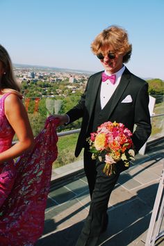 a man in a tuxedo and woman in a pink dress walking down stairs