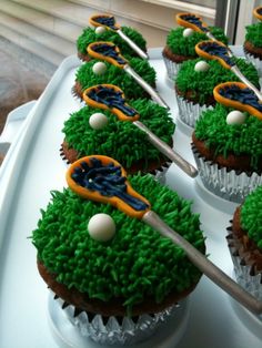 cupcakes decorated with green grass and blue icing are sitting on a tray