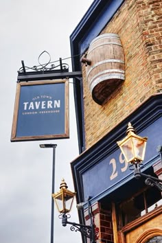 there is a sign for tavern on the side of this building with a barrel hanging from it's roof