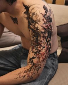 a man is sitting on the bed with his arm covered in ink