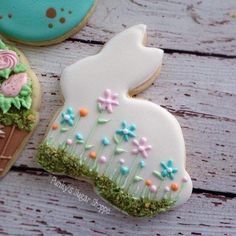 some decorated cookies are sitting on a wooden table and one has an ice cream cone in the shape of a bunny