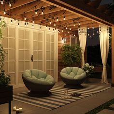 two green chairs sitting on top of a rug in front of a wooden structure with lights hanging from it