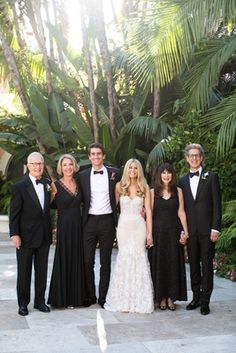 a group of people standing next to each other in front of some trees and bushes