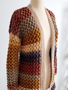 a mannequin wearing a multicolored knitted cardigan with open front