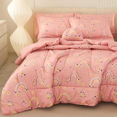 a bed with pink comforter and rainbows on it