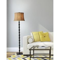 a living room with a white couch, yellow pillows and a lamp on the floor