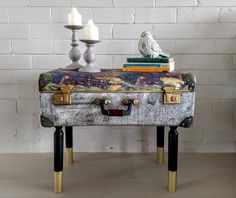 an old suitcase is turned into a table with candles and books on it, sitting next to a white brick wall