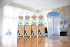 three baby bottles sitting on top of a table next to a blender