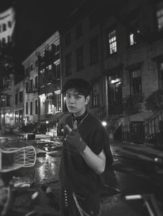 a young man standing in the middle of a street at night holding an open umbrella