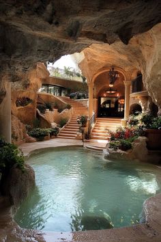 an indoor swimming pool with steps leading to the upper floor and above it is a waterfall