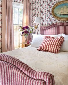 a large bed sitting in a bedroom next to a window covered in pink and white curtains