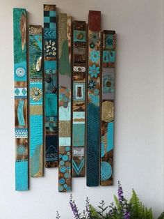 a wall hanging made out of different colored pieces of wood with flowers in the foreground