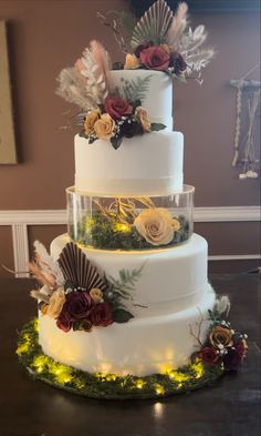 a three tiered wedding cake with flowers and feathers